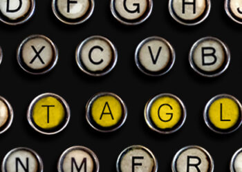 Teclado de uma máquina de escrever com a palavra "Tagline" destacada na cor amarela