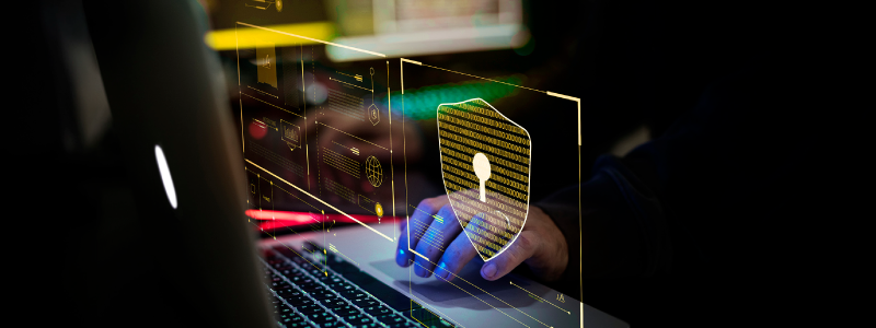 A imagem mostra uma pessoa que não aparece no enquadramento, apenas suas mãos digitando em um notebook com uma ilustração de um cadeado que remete a proteção de site contra ataque de hackers